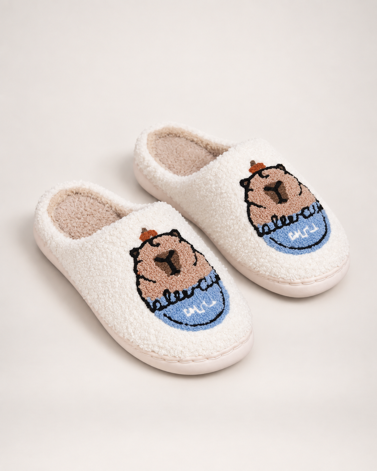 White embroidered capybara slippers shown as a complete matching pair