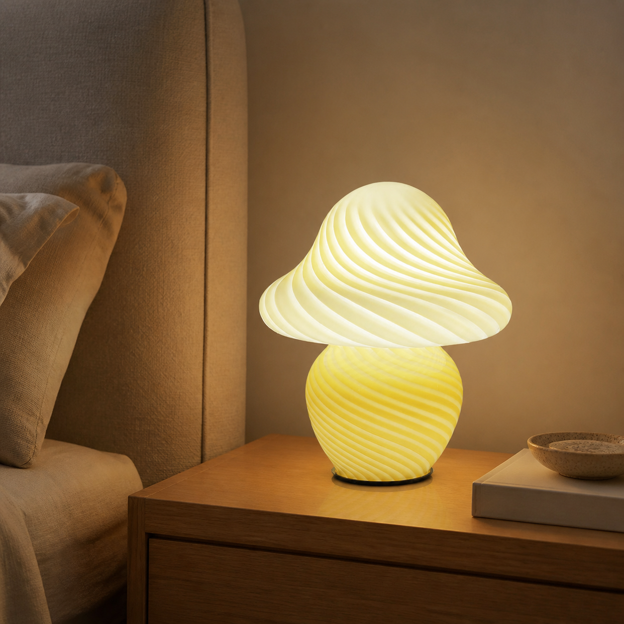 Yellow swirled glass mushroom table lamp glowing on an oak bedside table