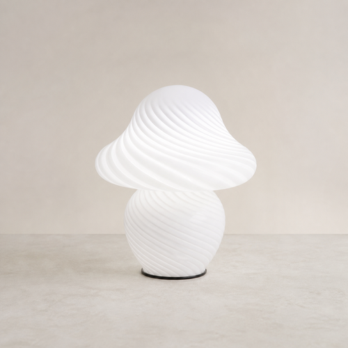 White swirled glass mushroom table lamp on a pale stone surface