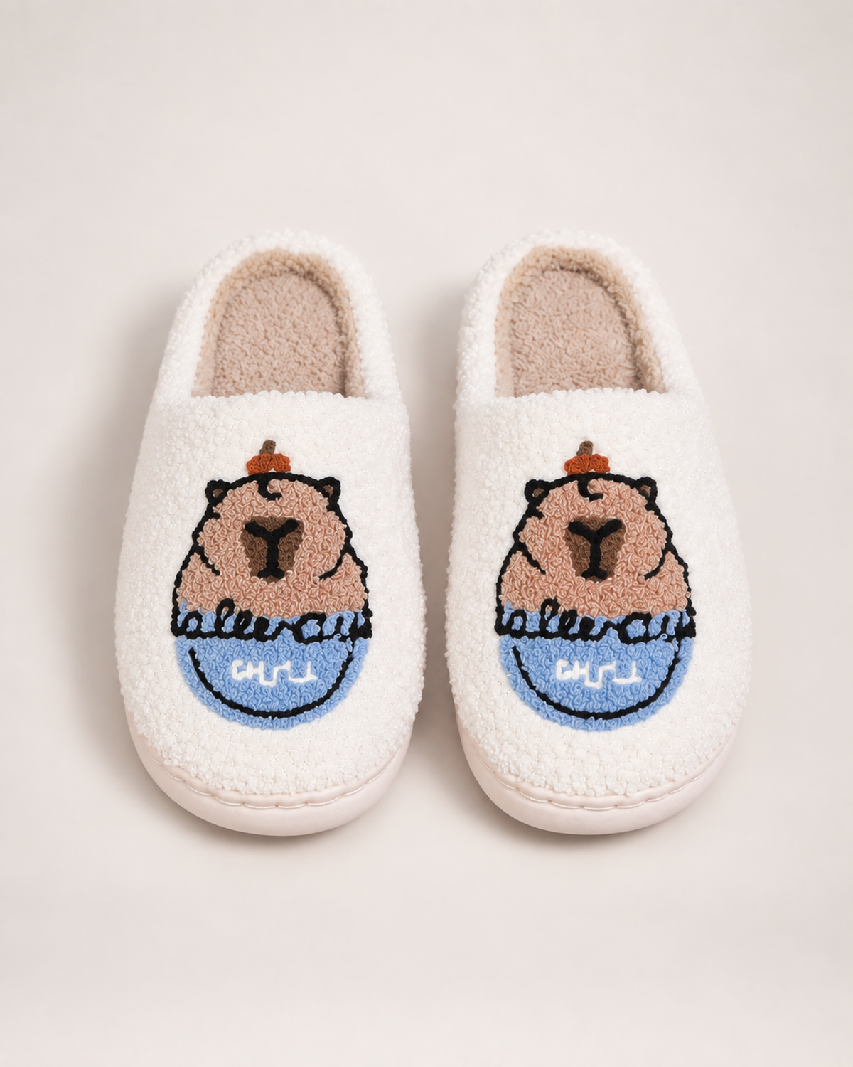 White embroidered capybara slippers shown from a front and top angle