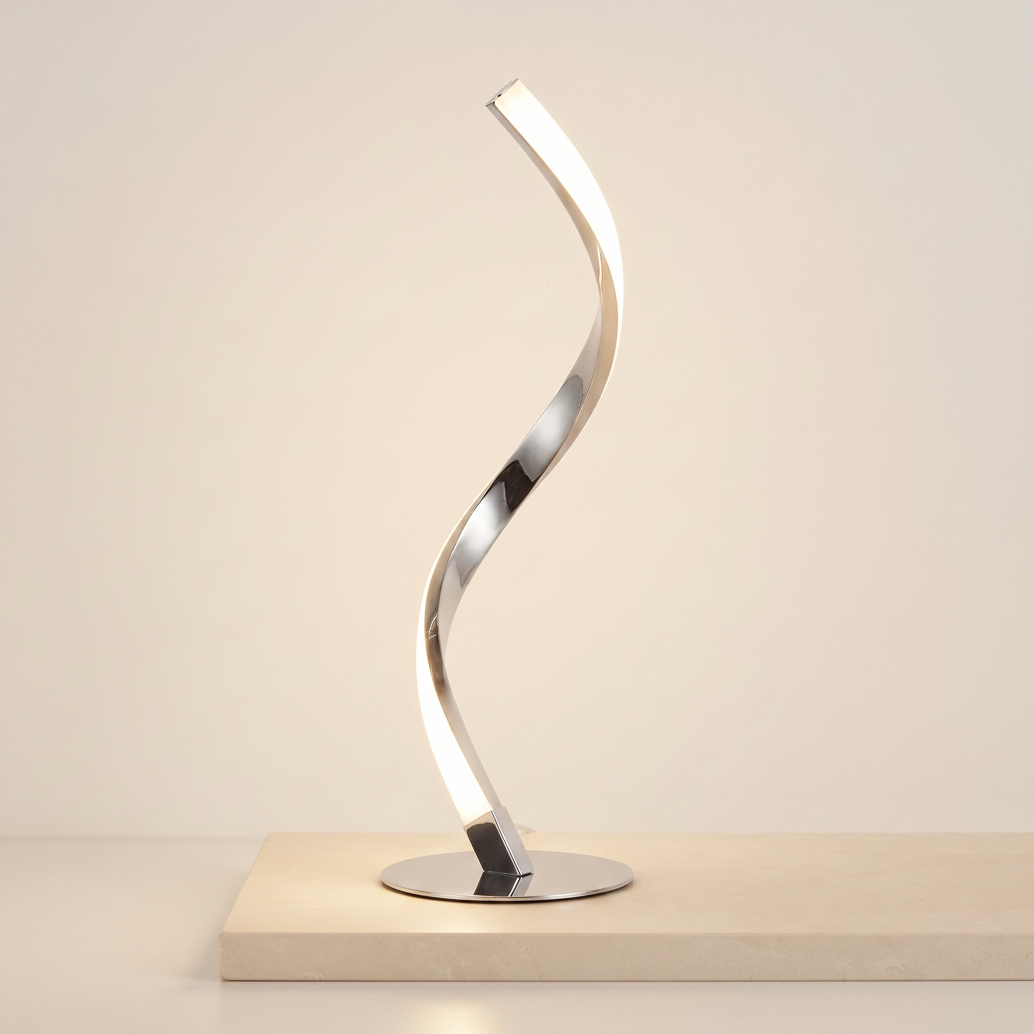 Chrome spiral LED table lamp on a pale stone plinth