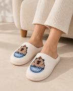 White embroidered capybara slippers worn indoors by an adult