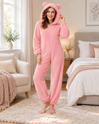 Women's pink bear-ear fleece onesie, bright bedroom lifestyle view