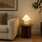 Yellow swirled glass mushroom lamp glowing beside a cream sofa