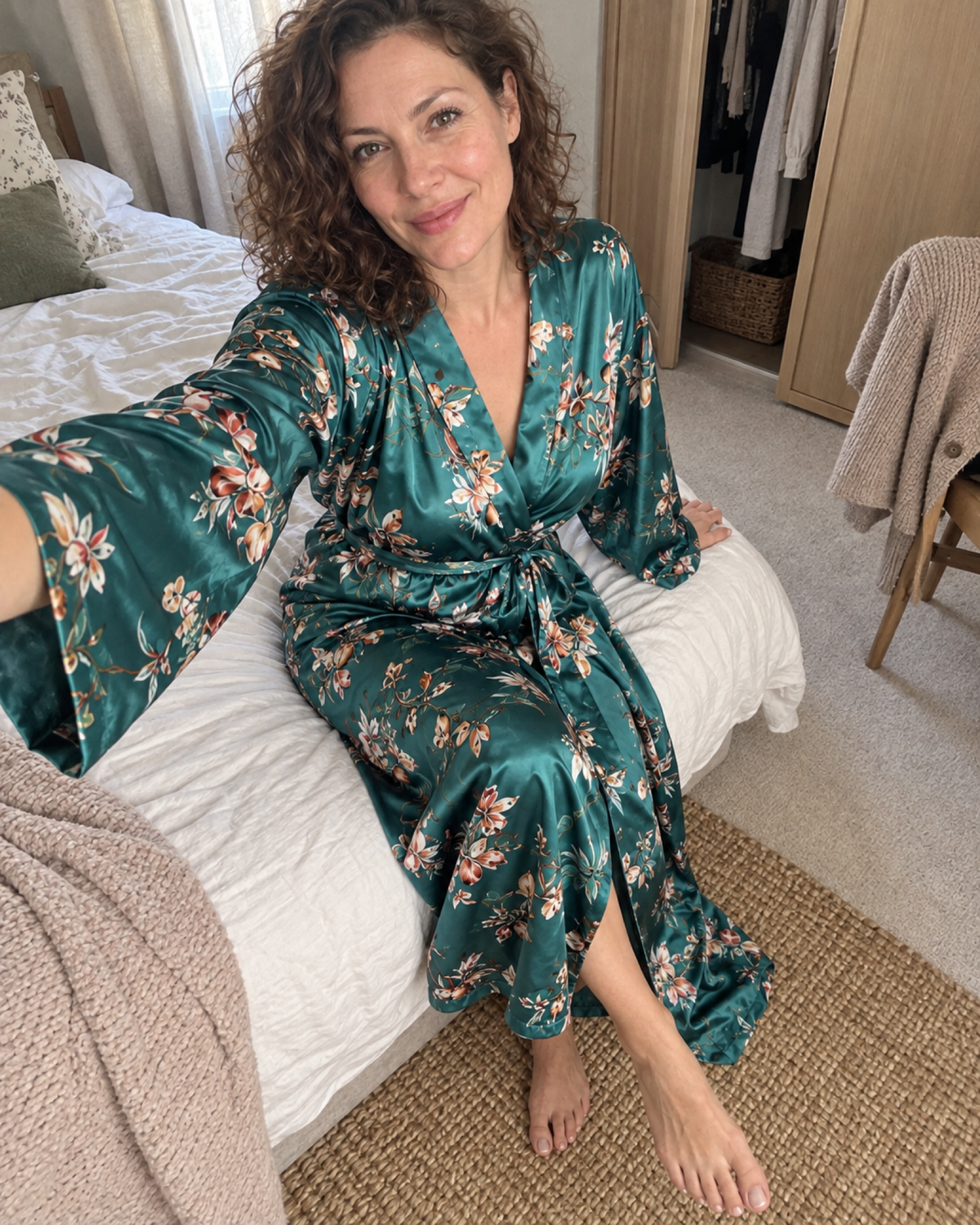 Woman taking a high-angle bedroom selfie in a teal floral satin dressing gown