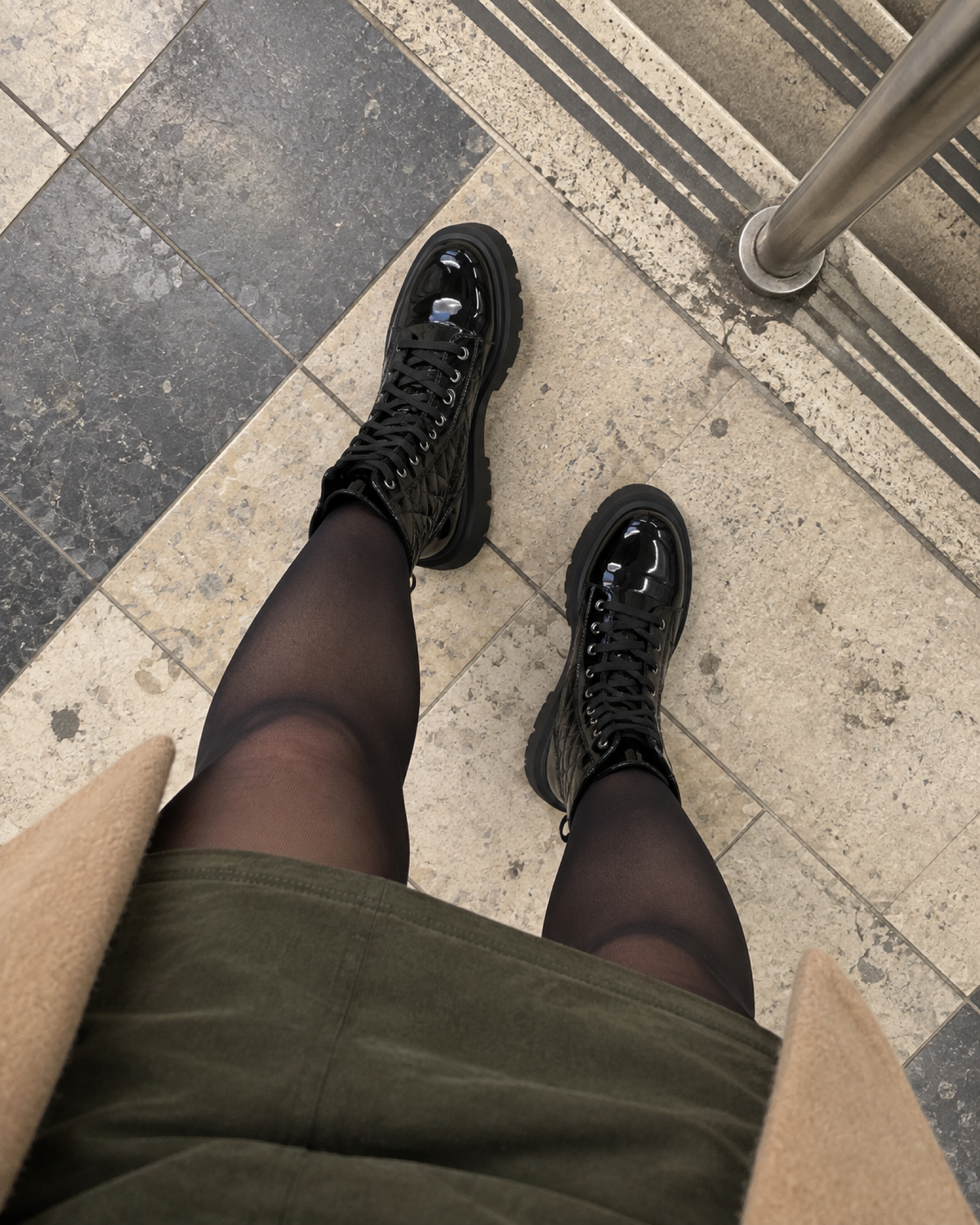 Downward outfit view of black quilted lace-up platform ankle boots