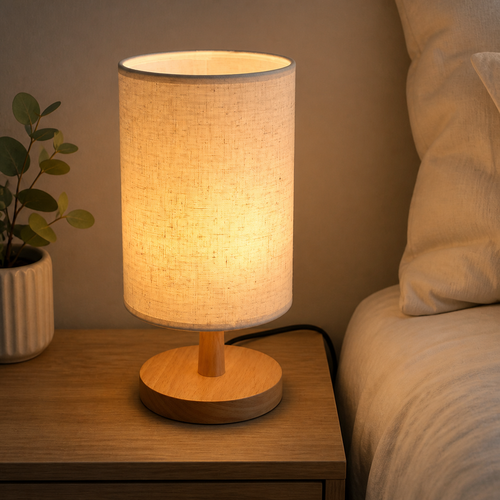 Wooden table lamp with a glowing beige fabric shade on a bedside table