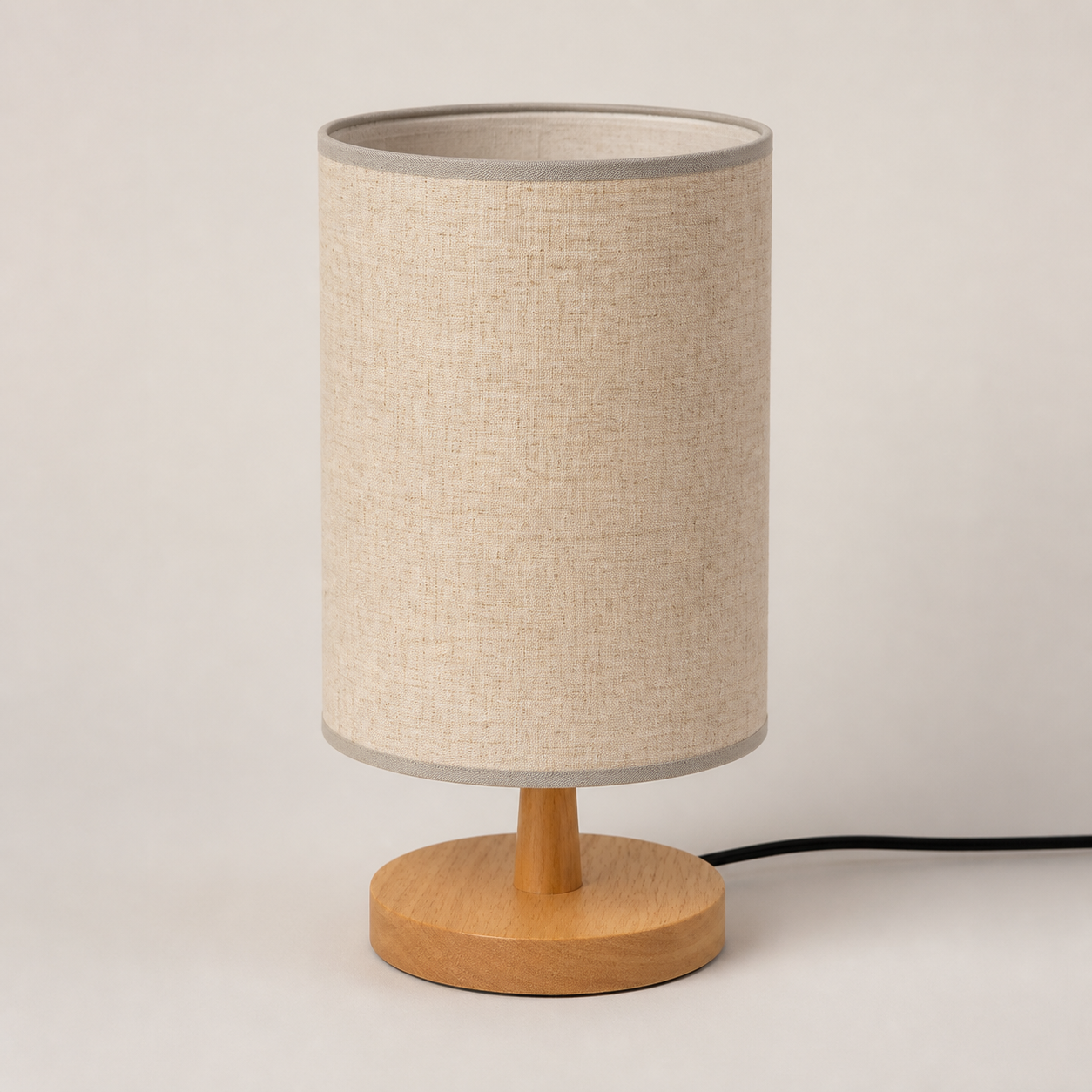 Round beige fabric-shade table lamp with wooden base, switched off